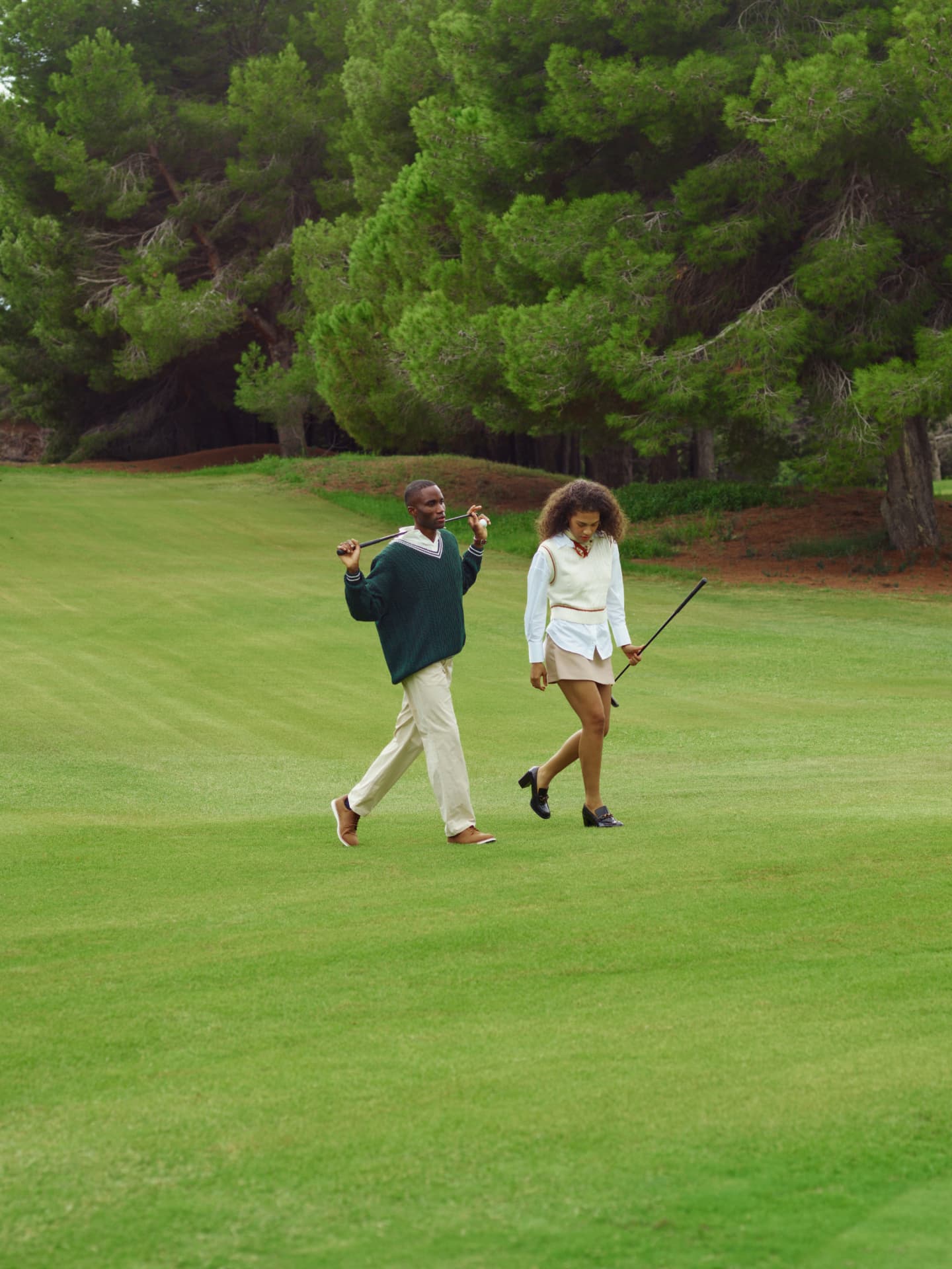 Two golfers walking across the fairway carrying their clubs